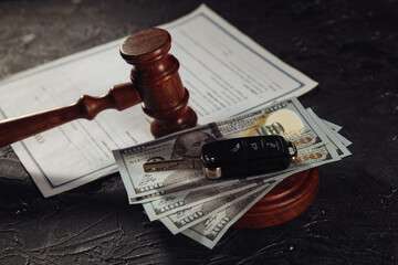 Car keys on dollar banknotes and wooden judge gavel with contract close-up.