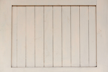 Weathered light gray paint texture on wooden planks of barred over window of renewed house on town street