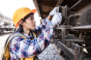 Engineers woman working on train garage site and using wrench for repair traction motor of train. Service and Technician concept.