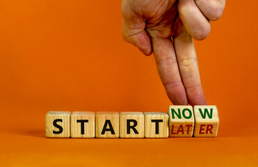 Start now or later symbol. Businessman turns wooden cubes and changes words 'start later' to 'start now'. Beautiful orange background, copy space. Business and start now or later concept.