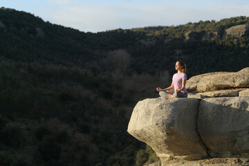 Fototapeta na wymiar Yogi doing yoga and meditating in the top of a cliff