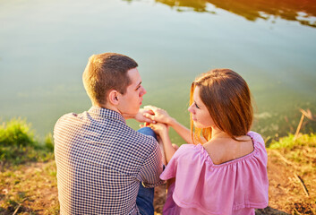 Obraz premium Romantic smiling couple in love dating at sunset at river.