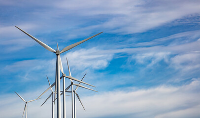 Wind turbines, renewable energy on  blue cloudy sky background. Wind farm