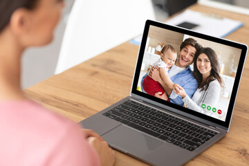 Young woman speaking to cheerful family with cute baby online, using laptop to communicate with her friends from home
