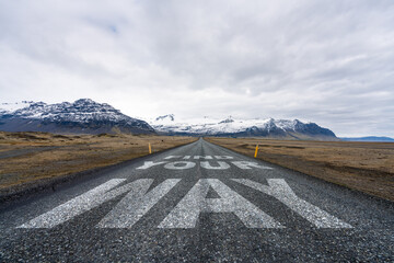 find your way text quote printed on asphalt road towards the mountains.
