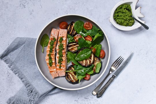 Grilled salmon with aubergine, tomato and spinach salad. Healthy dinner on the light background
