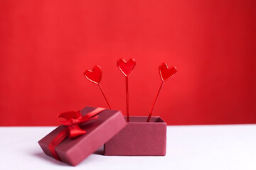 three hearts peeking out of a gift box