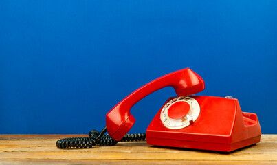 Red retro telephone on wooden table