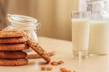 Close up of homemade raisin oatmeal cookies, raisins, jar with oat flakes  and glass of milk on the...