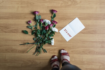 Woman legs in red high heel shoes standing near paper with it'over word on a floor with withered flowers. Concept.
