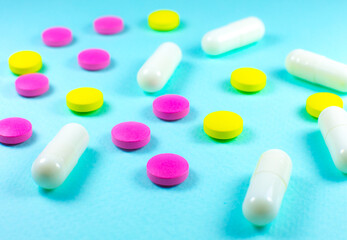 Colored pills and tablets on green background. Close up. Medical treatment concept.