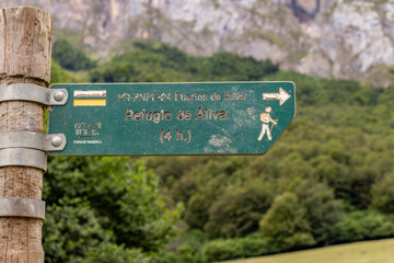 Fuente De, Spain - August 31, 2020: Wooden signpost with directional sign on hiking trail (Aliva refuge) at Fuente Dé, Picos de Europa, Asturias.