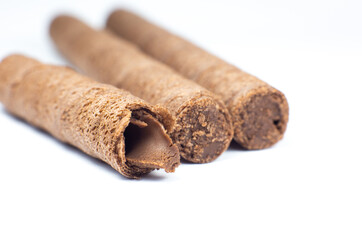 Sweet chocolate waffle rolls stick close up on white background.