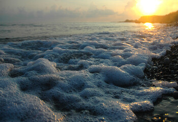 Sea surf at sunset. Rocky coast. Wet rocks. Waves and splashes. Frothy surf. Seascape in the evening.