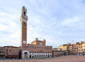 Obraz premium Torre del Mangia, a Renaissance tower and palace are lit by sunrise light in piazza del Campo in Siena, famous for the Palio street horse race, in Tuscany region of Italy.