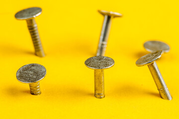 Metal nails close-up, lots of nails on a yellow background.