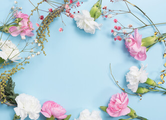 pink and white flowers together with ornamental plants form a composition on a blue background. copy space.