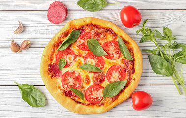 Pizza with ingredients on white table