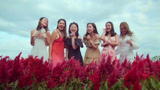 group of beatuful charming asian female friend wearing casual dress standing chat together with fun and cheerful in red flower farm clear sky background travel concept