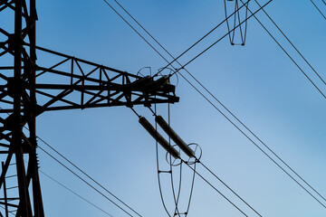 Electricity pylon with wires under high voltage. Landscape with high-voltage transmission towers. Blue sky background.