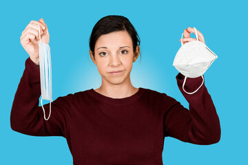 Junges M&auml;dchen h&auml;lt FFP2 Maske und Mund-Nasen-Schutz und schaut verwundert