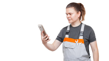 Fototapeta premium an employee in a gray uniform overalls with a wrench in his pocket holds a tablet mobile device for online service and purchases of goods, plumber isolated on a white background.