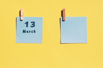 March 13st. Day of 13 month, calendar date. Two blue sheets for writing on a yellow background. Top view, copy space. Spring month, day of the year concept