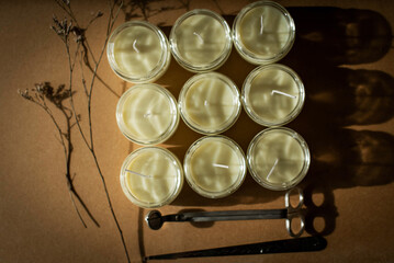 wooden wick candles. Handmade candle from paraffin and soy wax in glass with flowers and leaf on craft background. Let flay. Candle making. Top view.