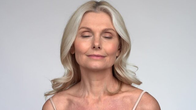 Confident beautiful fresh 50s middle aged mature woman looking at camera. Close up portrait. Anti age healthy face skin care beauty, older skincare cosmetic, cosmetology and dermatology concept.