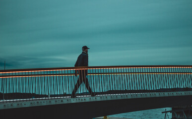 man crossing the footbridge at night
