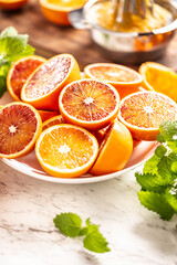Blood sicilian oranges sliced on white plate with fresh melissa