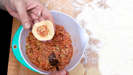 A girl puts meat in dumplings dough