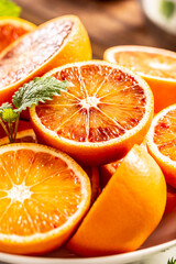 Fototapeta na wymiar Blood sicilian oranges sliced on white plate with fresh melissa
