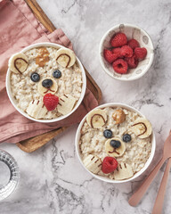 Oatmeal porridge bear with banana and berries, fun food art idea for kids food top view