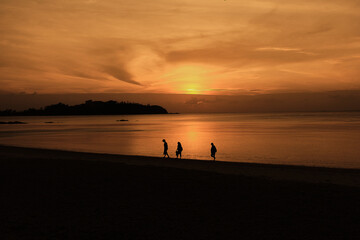 
silhouette of people walking in a sunset on the beach
