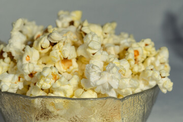 Air popcorn in a transparent bowl on a light background.