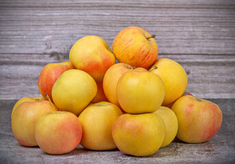 heap of golden ripe apples on wooden background
