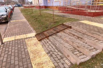 Elements of a barrier-free environment. Metal ramp and tactile tiles on the sidewalk.