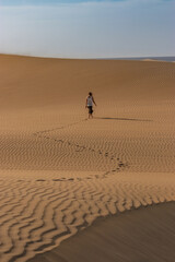 Fototapeta na wymiar Mujer caminando por las dunas