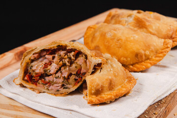 A Neapolitan empanada opened in half, in front of more empanadas.