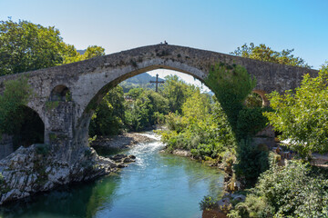 Cangas de Onis, Spain - September 4, 2020: The Roman Bridge of Cangas de Onís, the “Puente Vieyu” or “Puentón”. Medieval stone bridge over the Sella River, Asturias, Spain.