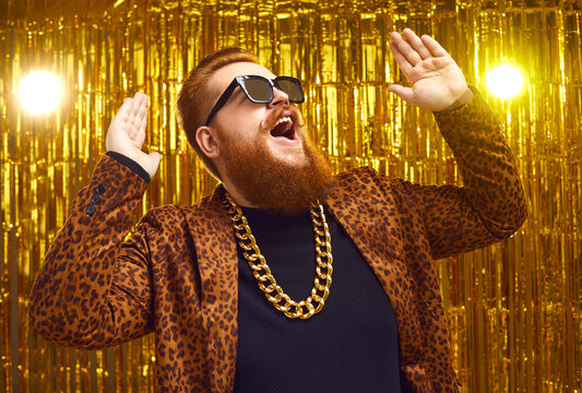 Excited Rich Redhead Man In Bling Golden Neck Chain And Cool Glasses DJing And Having Fun At Glamour Party. Happy Fashionable Showman With Beard And Handlebar Mustache Singing And Dancing On Stage