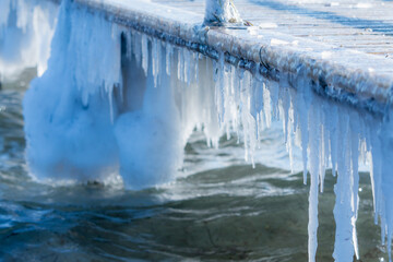 Icicles under the pier in Denmark day time closeup