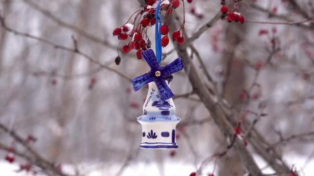 Blue ceramic Christmas toy bought in Amsterdam hangs on a branch
