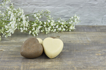 Handmade soap in the shape of a heart decorated with flowers on a wooden countertop.