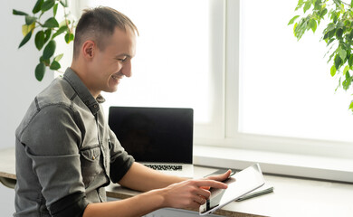 Smiling young man freelancer using laptop, studying online, working from home, happy casual guy...