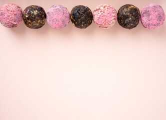 Homemade pink matcha dragon fruit energy balls, top view, healthy sweets made of nuts and date, prunes, sesame, cashew nuts, Pine nuts. Concept vegeterian diet candy brain food. Copy space.