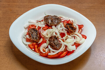 tomato salad with onions and sun-dried tomatoes on an old wooden table, vegan food