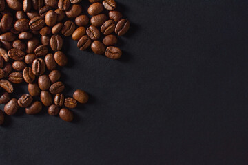 Fresh roasted coffee beans closeup on black stone background. Top view, flat lay with copy space