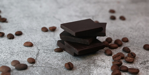 Close up of pieces of chocolate stacked over surrounded with coffee beans.